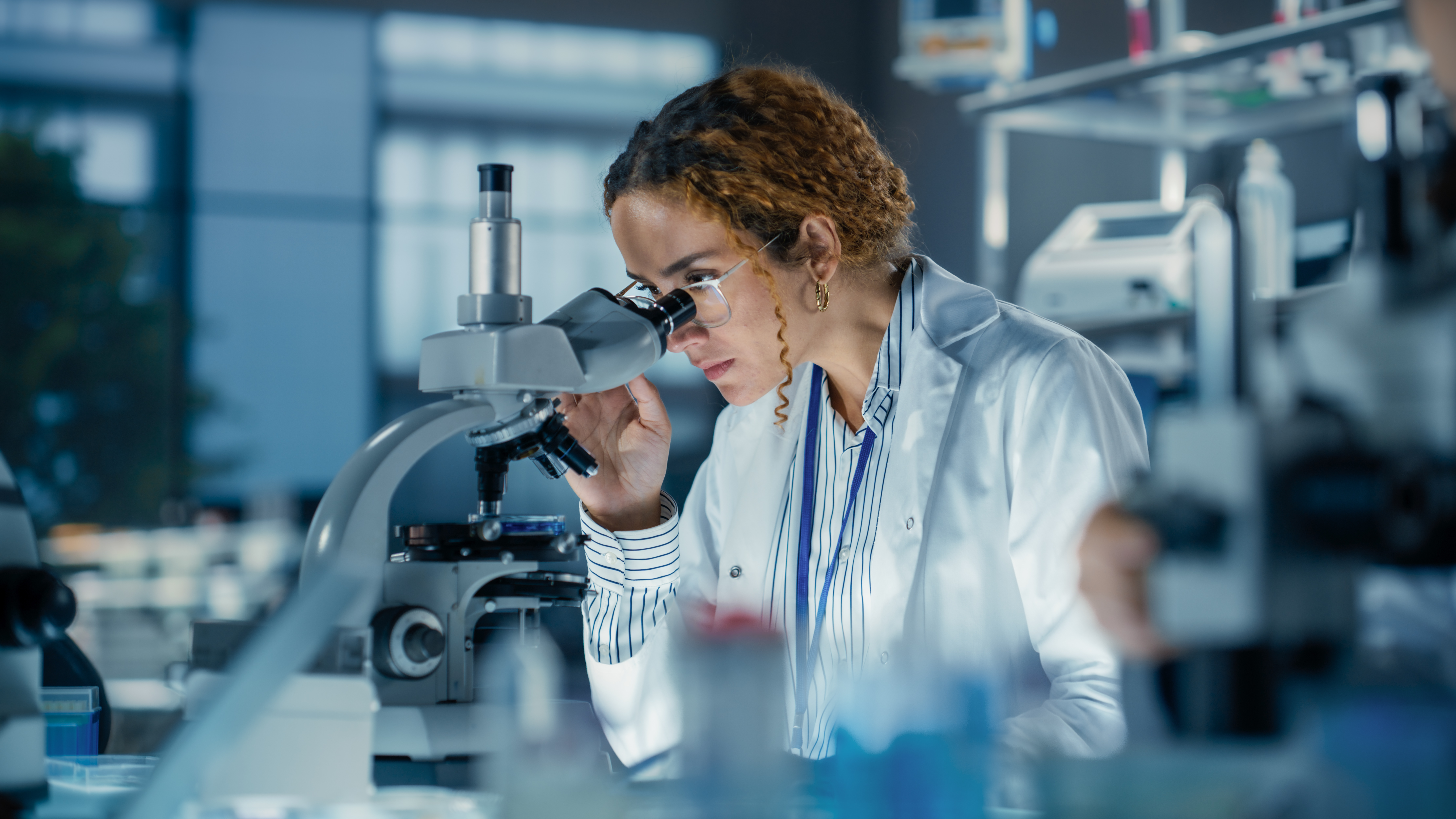 Portrait of a Student Working on a Research Project in College. Medical Research Scientist Looking at Biological Samples Under a Microscope in an Applied Science Laboratory