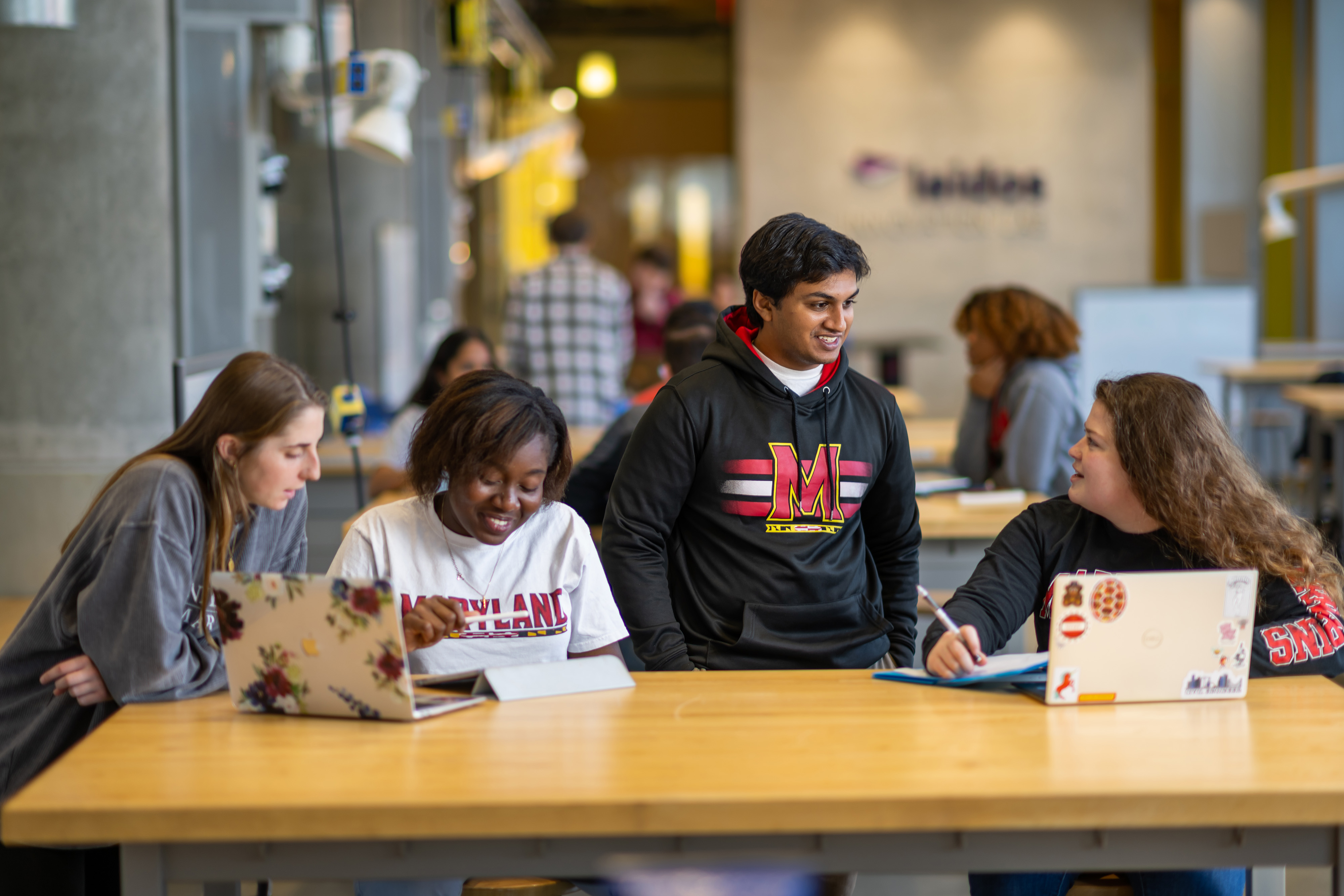 Four University of Maryland students work together on their laptops in the Leidos Lab in Clark Hall